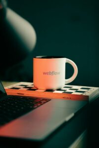 WebFlow vs WordPress 101- A Detailed Comparison for Digital Creators 16 a coffee mug sitting on top of a laptop computer