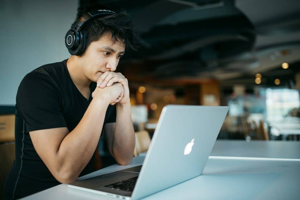 Udemy vs Coursera | The Ultimate Showdown Of These Popular Online Learning Platforms 16 man wearing headphones while sitting on chair in front of MacBook
