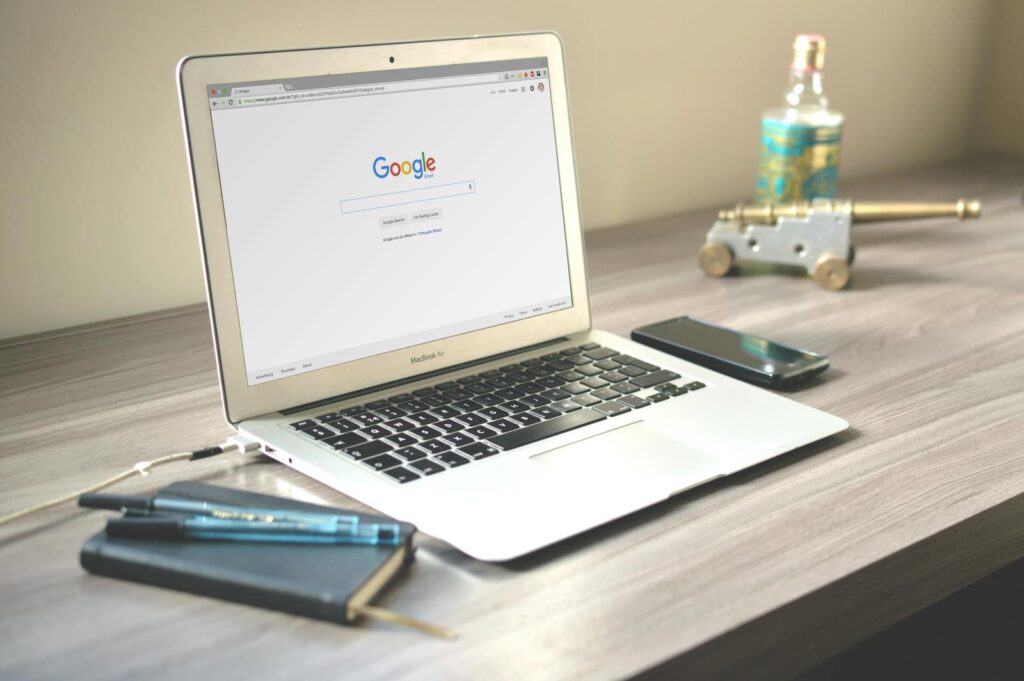 Best SEO Agency for Attorneys: Boost Your Law Firm’s Online Presence with Priceless Consulting 12 A neat workspace featuring a laptop displaying Google search, a smartphone, and a notebook on a wooden desk.