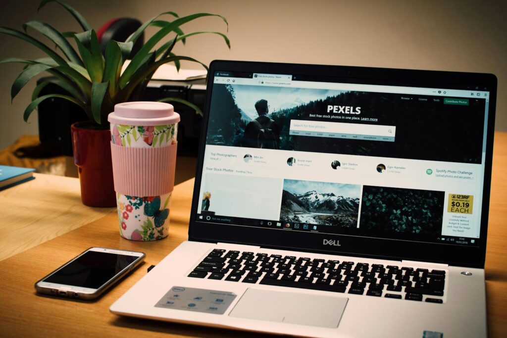 Choosing the Right Platform for Your Small Business: WordPress vs. Wix Website Builder 23 A tidy desk setting with a laptop showing a stock photo website and a smartphone.