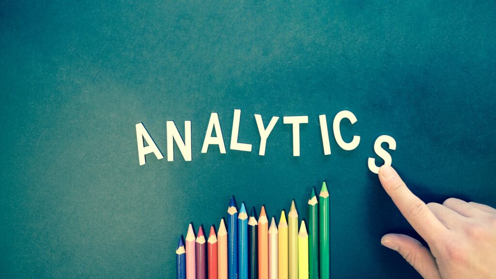 Mastering Your SEO Content Strategy: A Practical Guide for Success 10 Colored pencils and letters spelling 'ANALYTICS' on a textured background with a hand.