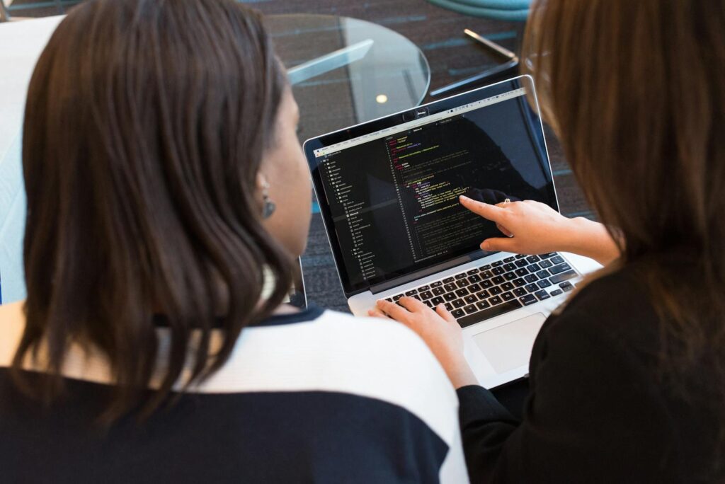 Mastering Ecommerce Website Development: A Practical Guide for Success 19 Two women working together on software programming indoors, focusing on code.