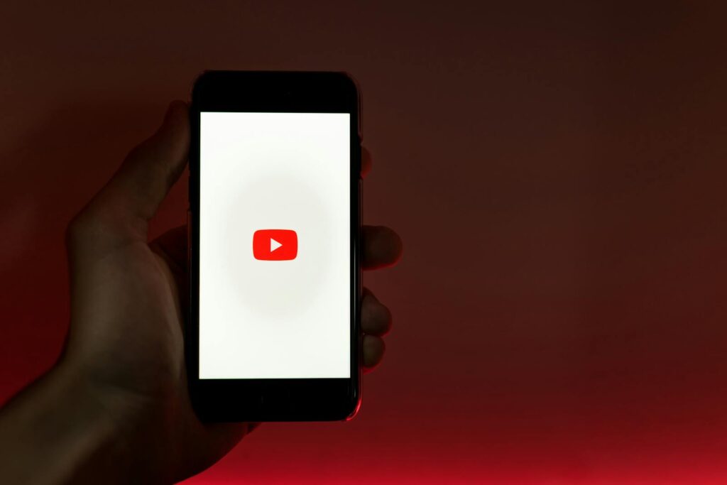 Is YouTube Considered Social Media? 21 A hand holding a smartphone displaying the YouTube app against a red background.