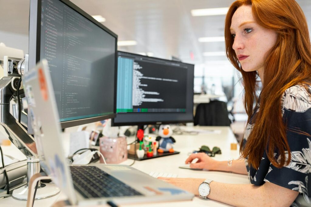 Mastering Ecommerce Website Development: A Practical Guide for Success 20 A focused female software engineer coding on dual monitors in a modern office.