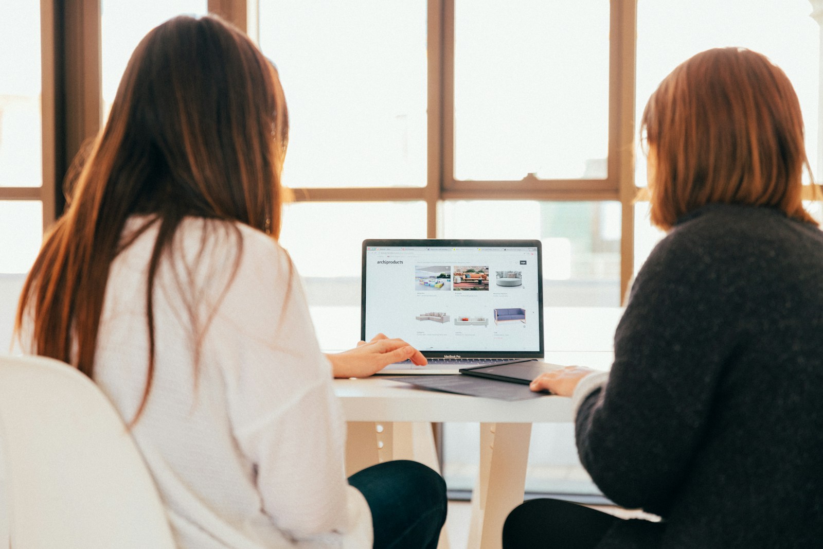 two women talking while looking at laptop computer web design services for small business