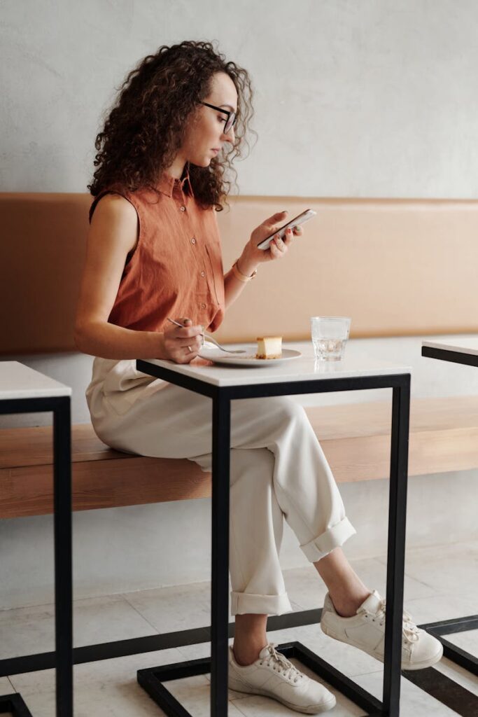 Social Media Presence: How to Elevate Your Business in 10 Simple Steps 21 A young woman enjoys a quiet moment at a coffee shop, checking her phone while seated.
