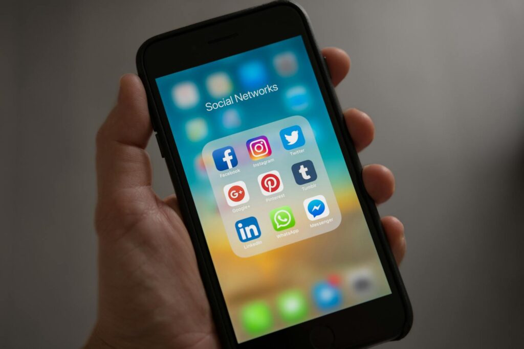 Social Media Presence: How to Elevate Your Business in 10 Simple Steps 22 A smartphone displaying various social media icons held in a hand, showcasing modern communication apps.